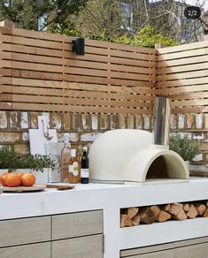 an outdoor pizza oven on top of a white counter next to some fruit and vegetables