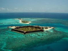 an island in the middle of the ocean surrounded by blue water and coral reefs