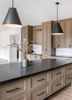 a large kitchen with an island and two pendant lights over it's counter tops