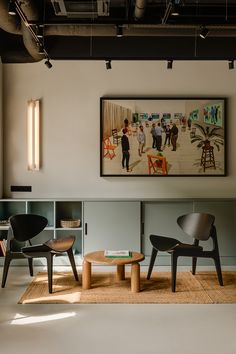 two chairs and a table in front of a painting hanging on the wall above them