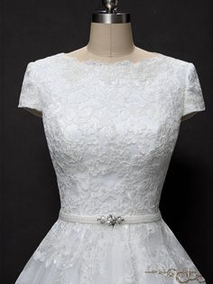 a white wedding dress on a mannequin with an embellished belt and beading