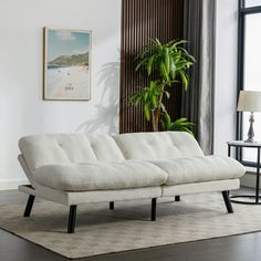 a white couch sitting on top of a rug in a living room next to a window