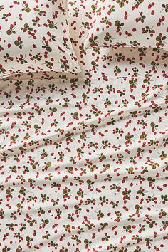 a white sheet with red and green berries on it, next to a pillow case