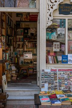 there are many books on display in the store front window and behind it is a bench