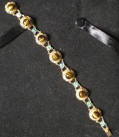 A very beautiful example of Chinese gold gilt on silver bracelet. This bracelet has bezel set round polished Tigereye stones With Enameling top and bottom and Flower links in between. Round tigereye cabochons measure 8mm with a Twist edge. There are 7 major links each set with Tigereye gold gilding all in tact . With 7 Alternate Enameled flower links . What a great gift for her absolutely near mint condition. Could become your family Heirloom . Get box with Purchase. Gold Cabochon Round Beads Jewelry, Gold Gemstone Beads And Cabochons, Gold Gemstone Round Beads, Gems And Cabochons, Luxury Beads, Gems, And Cabochons For Formal Occasions, Luxury Cabochon Round Stone Jewelry, Gold Jeweled Round Jewelry, Luxury Gold Gemstone Cabochons, Luxury Gold Bracelets With Gemstone Accents, Luxury Jeweled Gold Bracelets