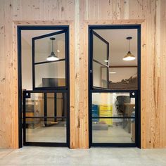 two open windows in the side of a wooden wall with black frames and glass doors