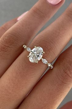 a woman's hand with a diamond ring on top of her finger and the other hand holding an engagement ring