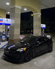 a black car parked in front of a gas station