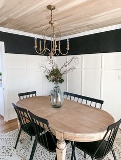 a dining room table with chairs and a vase filled with flowers on top of it