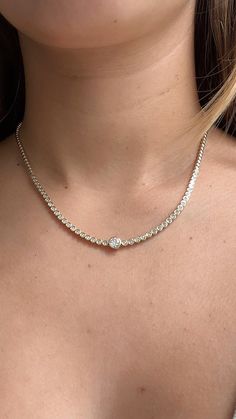 The Center Diamond Half Bezel Tennis Necklace is an elegant statement piece, featuring a stunning round diamond that draws the eye with its brilliance. The necklace is adorned with bezel-set diamonds that extend halfway around, adding a touch of timeless sparkle and sophistication. Available in 14k Yellow Gold, White Gold, and Rose Gold Diamond Total Carat Weight: approximately 1.60 ct Center Diamond: 0.50 ct Diamond Color: F-G Diamond Clarity: VS1 Length 16 inches Diamonds appear halfway around Luxury Formal Tennis Necklace With Bezel Setting, Rose Gold Diamond Tennis Necklace, Tennis Necklace Diamond, Classic Tennis Necklace With Bezel Setting, Luxury Classic Bezel Set Tennis Necklace, Elegant Bezel Set Tennis Necklace, Half Bezel, Diamond Tennis Necklace, Custom Wedding Rings