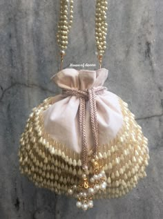 This is a beautiful handcrafted potli bag made with love.It has intricate handwork which showcases the Indian craftsmanship by our local artisans. It comes with a matching pearl handle. Details  - Both side handwork  - Fabric lining on the inside to keep your belongings safe  - Drawstring lock closure  - Detachable handle This clutch can be worn as a crossbody bag or a shoulder bag with the sling chain or can simply be carried in hand.It is spacious enough to carry mobile phones, lipsticks, Keys Bohemian Potli Bag For Receptions And Festivals, Reception Potli Bag With Pearl Embroidery, Elegant Potli Bag For Festivals And Receptions, Traditional Potli Bag With Dori Work For Reception, Elegant Bags For Festivals And Receptions, Elegant Bags For Reception And Festivals, Luxury Beige Shoulder Bag For Wedding, Traditional Gota Work Bag For Reception, Luxury Pearl Embroidered Potli Bag For Party