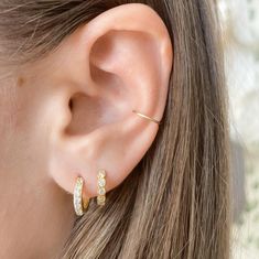 a close up of a person's ear with two small gold hoops on it