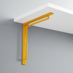 a yellow shelf is hanging on the wall next to a gray wall with white trim