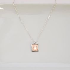 A touch of joy with this artfully designed necklace that is so perfect for gifting and every day wear. *  Hand-fabricated copper square edged with raised sterling silver, featuring tiny sterling silver butterfly set on top *  Sterling silver chain approx. 18"L with 1" extender, lobster clasp *  Pendant approx. 5/8"W x 3/4"L *  Made one at a time *  Due to the handmade nature of each piece, colors may vary slightly from photo. TURN AROUND TIME *  All of our jewelry pieces are made to order, and our turn around time is approximately 6-10 days.  If you need a rush order, please contact us to see if we can meet your deadline GIFTS - WE LOVE SENDING THEM FOR YOU! *  All jewelry pieces are nicely packaged in jewelry boxes with ribbon or tulle and ready to gift.  Prices are not included in the sh Spiritual Birth Flower Necklace Gift For Her, Nature-inspired Flower Charm Necklace For Gift, Handmade Nature-inspired Necklaces For Mother's Day, Spiritual Hand Stamped Pendant Necklace, Mother's Day Nature-inspired Pendant Necklace, Dainty Handmade Small Necklace, Rose Gold Necklace Gift For Mom, Delicate Hand Stamped Necklace For Gift, Handmade Small Charm Necklaces As Gift