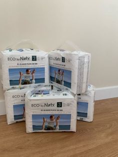 four packs of eco by natty diapers sitting on top of a wooden floor