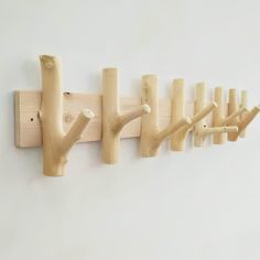 a wall mounted coat rack with five wooden hooks