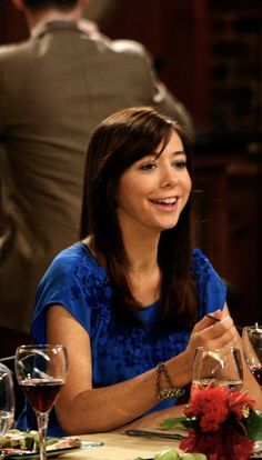 a woman sitting at a table with wine glasses