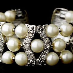 a close up of a bracelet with pearls and diamonds on it's sides,