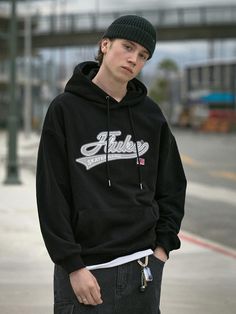 a young man in a black hoodie is standing on the sidewalk with his skateboard