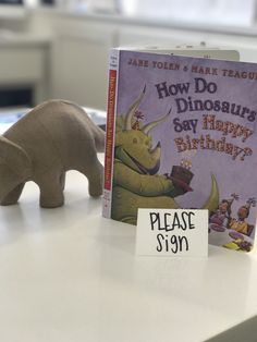 a book about how do dinosaurs say happy birthday with an elephant figurine next to it