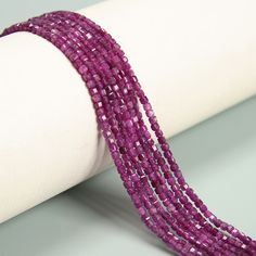 three strands of purple glass beads on a white surface