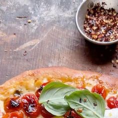 a pizza sitting on top of a wooden cutting board next to a bowl of food