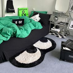 a black and white bed with green comforter in a small room next to other items