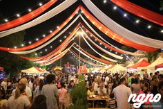 a crowd of people standing around tables under red, white and blue canopyed tents