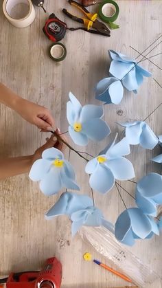 a person is cutting paper flowers on a table with scissors and other crafting supplies