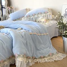 there is a bed with blue sheets and pink flowers on the comforter, along with a teddy bear