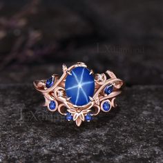 a ring with blue stones and leaves on it sitting on top of a stone surface