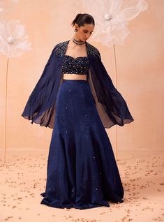 This chic cape-style lehenga set features a hand-embroidered blouse with a cutwork neckline, paired with an embroidered cape jacket. The lehenga completes the ensemble, offering a blend of sophisticated craftsmanship and contemporary style, perfect for any elegant occasion. Organza Gown Designs, Cape Lehenga, Pre Bridal, Organza Gown, Hand Embroidered Blouse, Embroidered Cape, Black Lehenga, Blue Cape, Organza Gowns