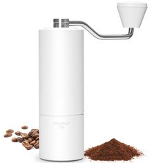 the coffee grinder is next to some brown beans and cinnamons on a white background