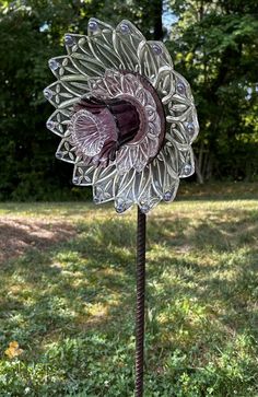 a glass sunflower sitting on top of a metal pole in the middle of a field