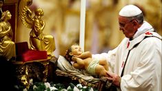 the pope is holding a baby in his lap as he stands next to a statue