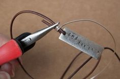 a person holding a pair of scissors and wire with a name tag attached to it