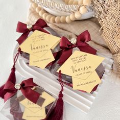 three small tags with red ribbons tied to them sitting on a white tray next to burlap