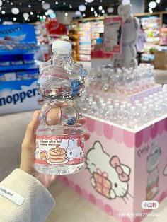 a person holding up a hello kitty water bottle in front of a store display case