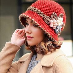 a woman wearing a red knitted hat with flowers on the brim and side