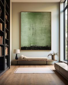 a large green painting hangs in the corner of a room next to a couch and bookshelf