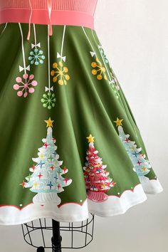 a green skirt with christmas trees on it and pink trimming around the neckline