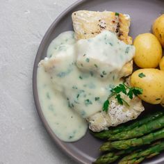 a plate with asparagus, potatoes and chicken on it