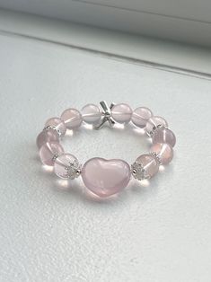 ❤️Add a touch of elegance and tranquility to your jewelry collection with this beautiful Rose Quartz bracelet. Crafted from smooth, round beads, this bracelet captures the gentle pink hue of Rose Quartz, known as the stone of universal love. ▫️Material: Genuine Rose Quartz Round Beads; Heart-shaped Rose Quartz, DIY accessories  ▫️Bead Size: 12mm ▫️Rose quartz heart size: 15mm*10mm ▫️Bracelet length: fits wrist length 15cm (6in)+  ✅Care Instructions: ✔️Keep away from harsh chemicals and prolonged exposure to water. ✔️Clean with a soft cloth to maintain its natural shine. 🔺Please note:  ☑️All photos are taken in the natural daylight with no filter applied. ☑️Each bead in the bracelet is unique. The presence of dark spots, white lines and yellow hues add to the natural beauty of your bracele Adjustable Heart Bracelet With Round Beads, Adjustable Heart Bracelet With 8mm Round Beads, Rose Quartz Round Beads Jewelry For Valentine's Day, Elegant Heart-shaped Beaded Friendship Bracelets, Valentine's Day Rose Quartz Beaded Jewelry, Elegant Pink Beaded Bracelets With Heart Beads, Elegant Beaded Heart-shaped Stretch Bracelet, Elegant Pink Heart Beaded Bracelets, Elegant Pink Heart-shaped Beaded Bracelets