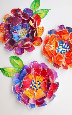 three flowers made out of colored paper on top of a white surface with the words real colors