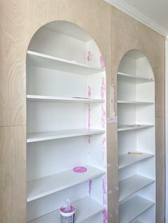 two white shelves with pink paint on them in a room that is being renovated and painted