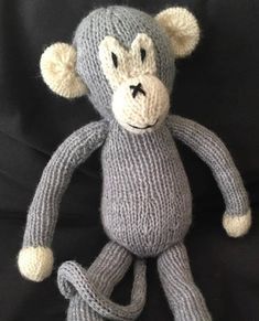 a knitted monkey sitting on top of a black blanket