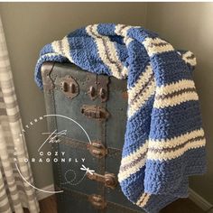 an old suitcase is covered with a blue and white blanket