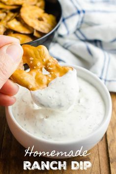 a hand dipping ranch dip into a bowl