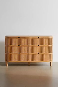 a wooden dresser sitting on top of a hard wood floor next to a white wall