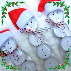 some white buttons are wrapped in plastic and have santa hats on them with red string